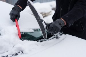 driver cleaning ice off windshield
